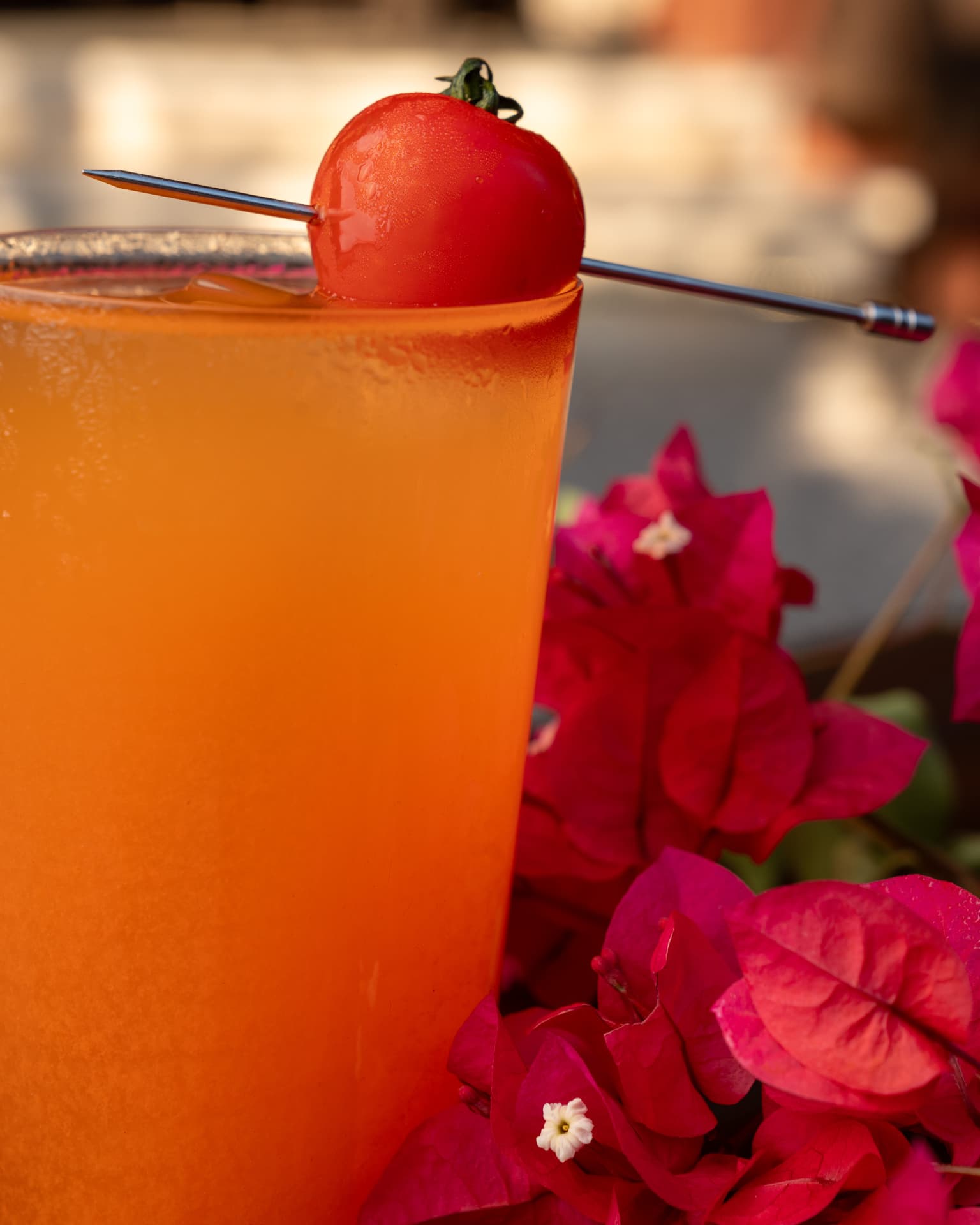 Close-up of a vivid tomato cocktail among bougainvillea at TAMAN